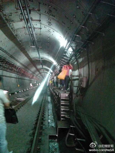 Passengers walk through an emergency passageway as the train was evacuated on Sunday, September 8, 2013. A train running on Hangzhou subway's line one powered down in the tunnel-way that travels under the Qiantangjiang river. [Photo: weibo.com]