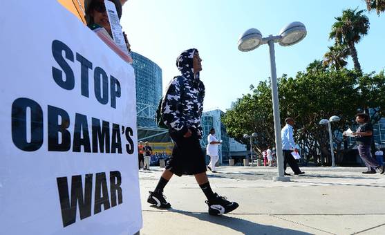 Pedestrians walk past a placard that reads 'Stop Obama's War' outside the LA Covention Center in Los Angeles on September 9, 2013 in California, as US President Barack Obama said a Russian plan to secure Syria's chemical weapons could be a 'significant breakthrough' but warned he had not taken US strikes off the table. [Xinhua]