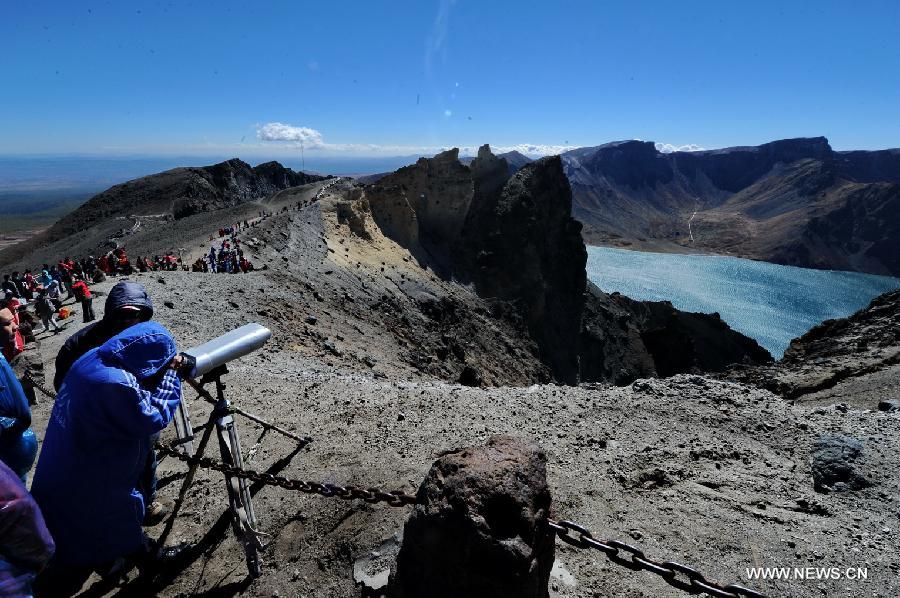 A visitor views the scenery of Tianchi Lake by telescope on the Changbai Mountain, northeast China&apos;s Jilin Province, Sept. 15, 2013. The Changbai Mountain will witness a travel peak as the Mid-Autumn Festival and the National Day holidays are coming. 