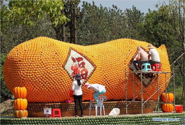 People work on a 'pumpkin peanut' in Seyuan of Nantong, east China's Jiangsu Province, Sept. 16, 2013. Seyuan will hold its first All-Saint's Day Pumpkin Festival from Sept. 25 to Nov. 25, in which more than 30,000 artificial pumpkins will form a pumpkin kingdom. [Photo: Xinhua/Xu Congjun] 