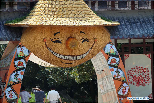 People walk past a gate formed by artificial pumpkins and other plants in Seyuan of Nantong, east China's Jiangsu Province, Sept. 16, 2013. Seyuan will hold its first All-Saint's Day Pumpkin Festival from Sept. 25 to Nov. 25, in which more than 30,000 artificial pumpkins will form a pumpkin kingdom. [Photo: Xinhua/Xu Congjun] 