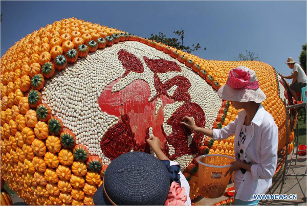 People work on a 'pumpkin peanut' in Seyuan of Nantong, east China's Jiangsu Province, Sept. 16, 2013. Seyuan will hold its first All-Saint's Day Pumpkin Festival from Sept. 25 to Nov. 25, in which more than 30,000 artificial pumpkins will form a pumpkin kingdom. [Photo: Xinhua/