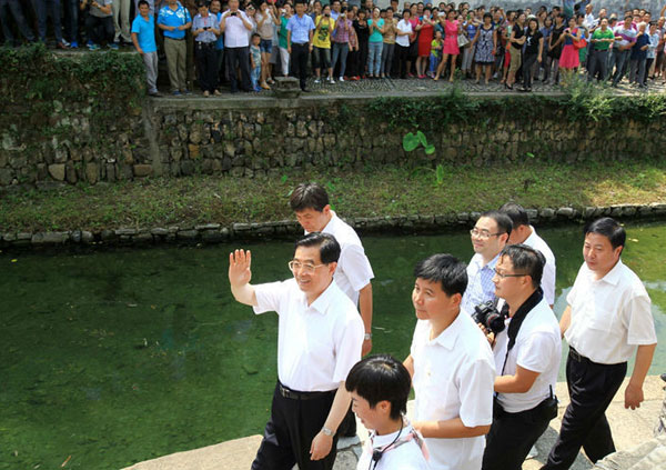 胡锦涛在途中向父老乡亲挥手。