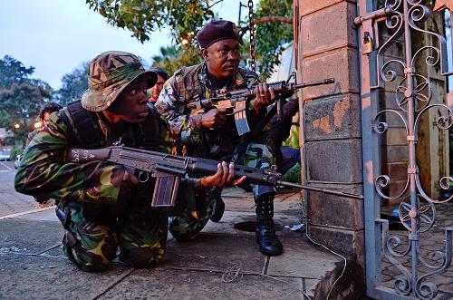 Kenyan soldiers take cover after heavy gunfire near Westgate mall in Nairobi on September 23, 2013. Somali Shebab militants on September 23 threatened to kill hostages they are holding in the Nairobi shopping mall as Kenyan troops move to end their siege. [Xinhua]