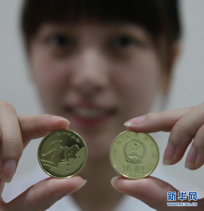 9月23日，在上海金山区象州路上的一家农业银行，一名工作人员正在展示“和”字书法——行书普通纪念币。当日，中国人民银行发行“和”字书法——行书普通纪念币。该币面额为5元，发行数量为5000万枚。