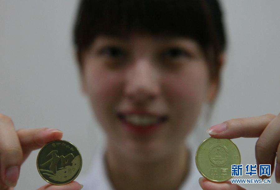 9月23日，在上海金山区象州路上的一家农业银行，一名工作人员正在展示“和”字书法——行书普通纪念币。当日，中国人民银行发行“和”字书法——行书普通纪念币。该币面额为5元，发行数量为5000万枚。