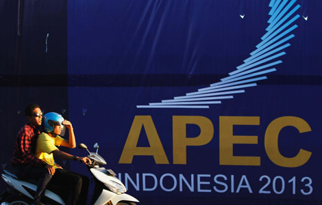Girls ride a motorcycle past a banner near the venue of the upcoming Asian Pacific Economic Cooperation (APEC) Summit in Nusa Dua, Bali island October 4, 2013.[Photo/Agencies] 