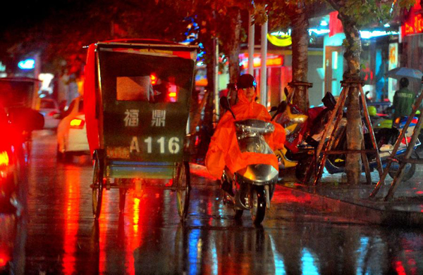 People ride in rain in Fuding City, southeast China's Fujian Province, Oct. 6, 2013. 