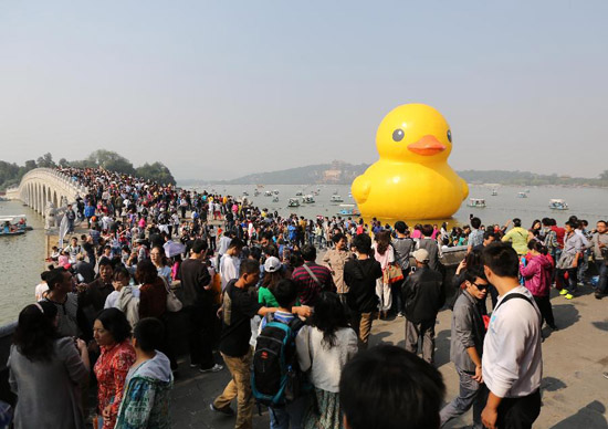 Tourists visit the giant yellow rubber duck, brainchild of Dutch artist Florentijn Hofman, at the Summer Palace in Beijing, capital of China, Oct. 3, 2013, also the third day of the seven-day National Day holiday. [Xinhua/Liang Zhiqiang]