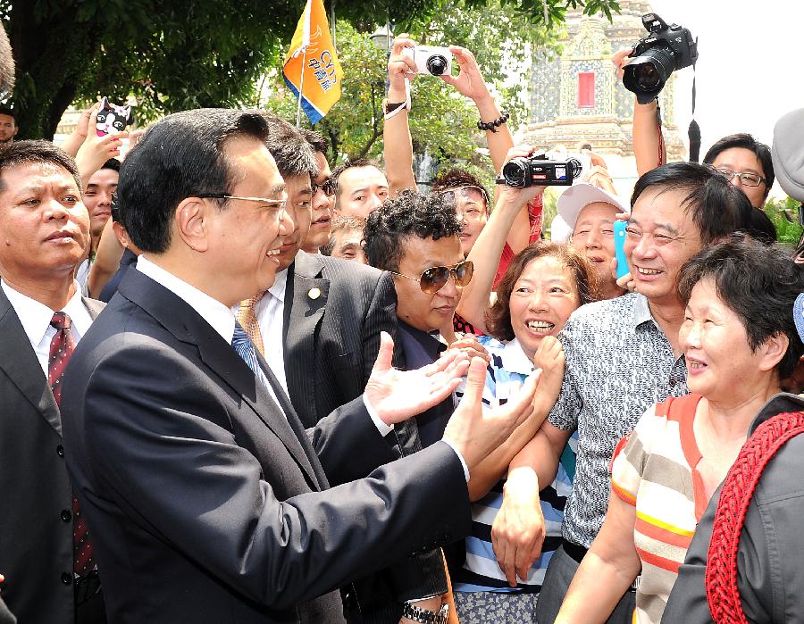 Chinese Premier Li Keqiang (L front) talks with Chinese tourists while visiting the Temple of The Reclining Buddha in Bangkok, Thailand, Oct. 12, 2013. [Xinhua]