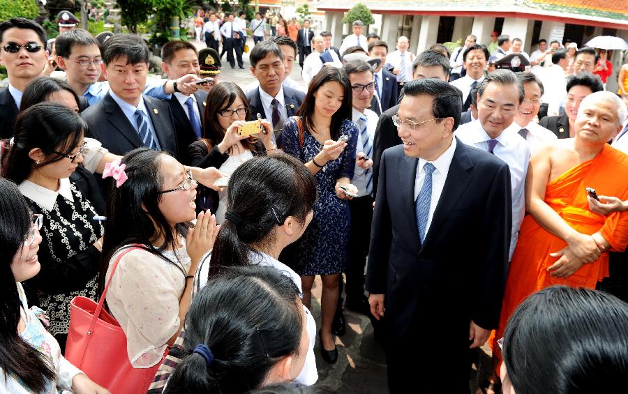 Chinese Premier Li Keqiang talks with Chinese tourists while visiting the Temple of The Reclining Buddha in Bangkok, Thailand, Oct. 12, 2013. [Xinhua]