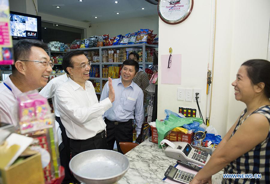 Chinese Premier Li Keqiang (2nd L) talks with a local store owner as he takes a walk near his hotel in Hanoi, Vietnam, Oct. 14, 2013. Li landed here Sunday for an official visit to Vietnam.