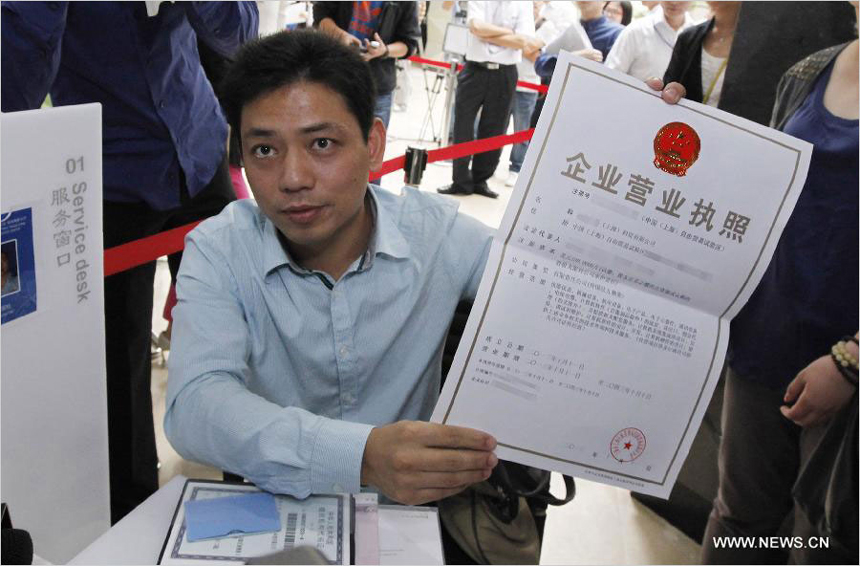 An enterprise representative shows the business registration he just received at the service lobby of Shanghai Free Trade Zone (FTZ) in Shanghai, east China, Oct. 14, 2013. The newly-launched Shanghai pilot free trade zone (FTZ) started offering enterprise registration service recently.