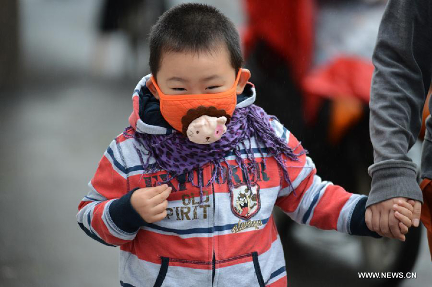 A young boy keeps warm as a cold wave hit Nanjing, capital of east China&apos;s Jiangsu Proince, Oct. 15, 2013.