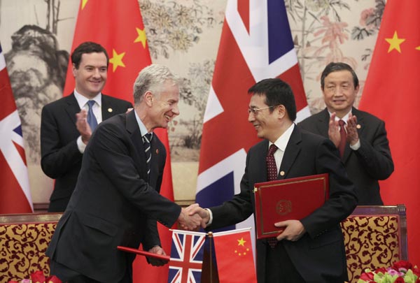 Vice-Premier Ma Kai (right) and UK Chancellor of the Exchequer George Osborne oversee the signing of an agreement between the two countries in Beijing on Tuesday. The UK is the most popular destination in Europe for Chinese investment. [Zou Hong / China Daily]