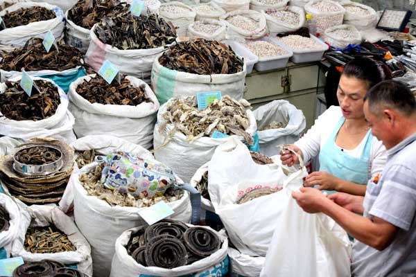 Businessmen select materials for traditional Chinese medicine at a TCM trade center in Bozhou, Anhui province.[Liu Qinli / for China Daily]