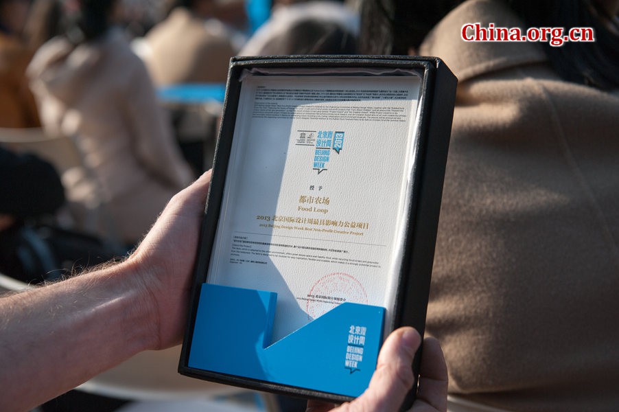 A guest, project manager of Food Loop, a modern technology farming project, shows his award from the Beijing Design Week committee on Thursday at the Farewell, Rubber Duck ceremony at the Summer Palace in Beijing. [Photo / China.org.cn]