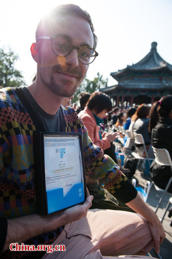 A guest, project manager of Food Loop, a modern technology farming project, shows his award from the Beijing Design Week committee on Thursday at the Farewell, Rubber Duck ceremony at the Summer Palace in Beijing. [Photo / China.org.cn]