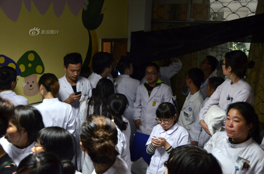 Doctors and nurses at No. 1 Hospital in Wenling, Zhejiang Province, gather at the temporary autopsy room on Sunday, guarding the body of Dr. Wang Yunjie, who was stabbed to death two days earlier while at work. Only a few staff members held their posts. [Photo / Sina]