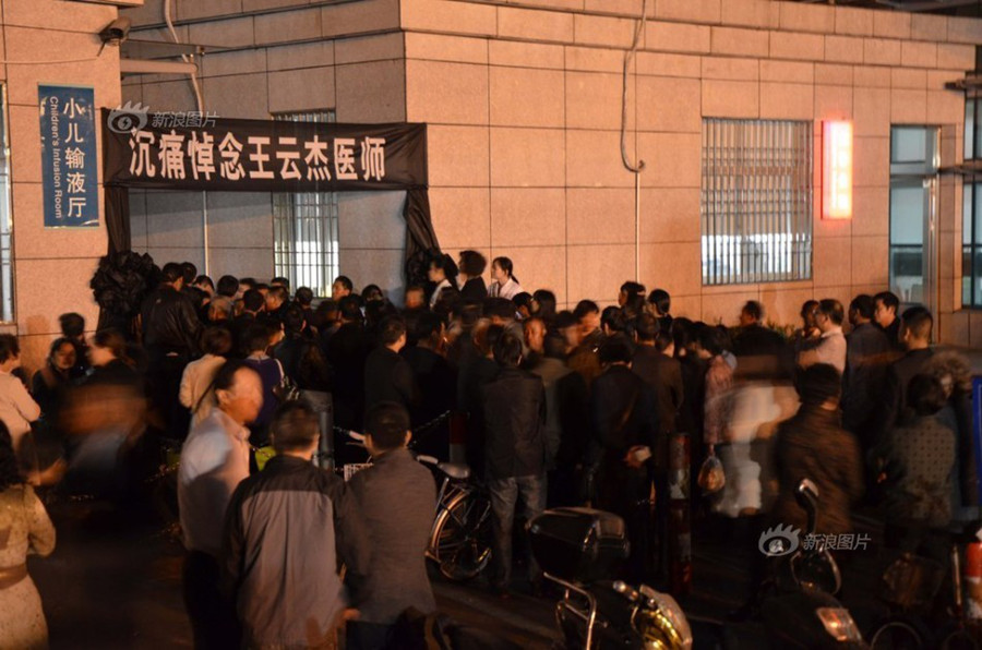 Doctors and nurses at No. 1 Hospital in Wenling, Zhejiang Province, gather at the temporary autopsy room on Sunday, guarding the body of Dr. Wang Yunjie, who was stabbed to death two days earlier while at work. Only a few staff members held their posts. [Photo / Sina]