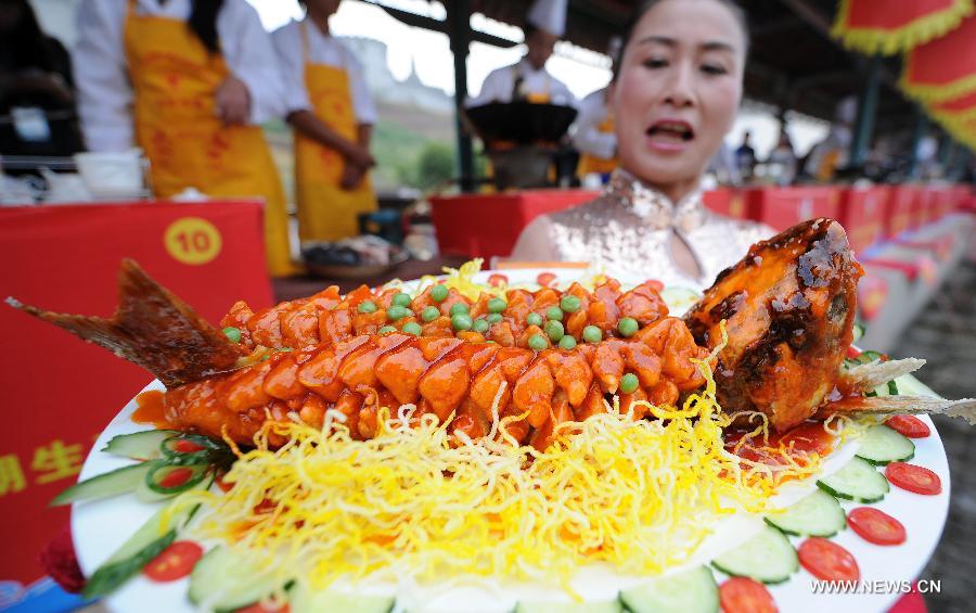 A worker displays the dish of sweet and sour fish at a fish cooking contest held in Wan'an County, east China's Jiangxi Province, Oct. 30, 2013.