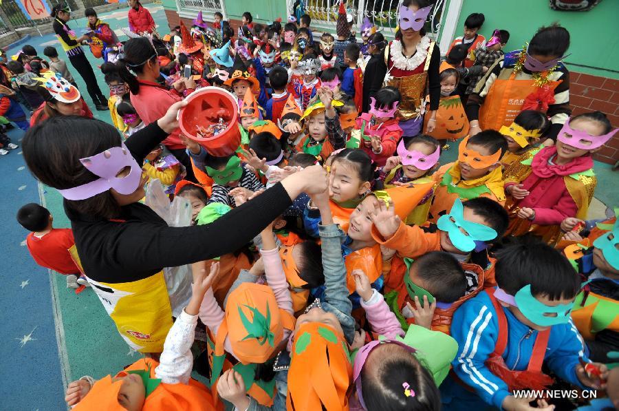 A teacher distributes candies to children to greet the Halloween in a kindergarten in Handan City, north China's Hebei Province, Oct. 31. The World Thrift Day fell on Thursday, a day before the All-Saint's Day this year. 