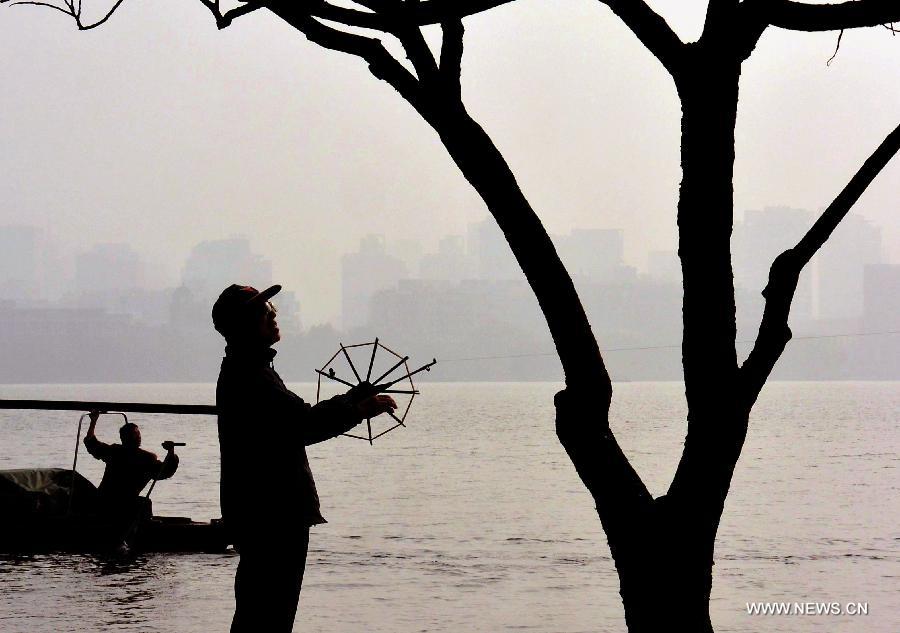 A man flies a kite by the West Lake in Hangzhou, capital of east China's Zhejiang Province, Nov. 4, 2013