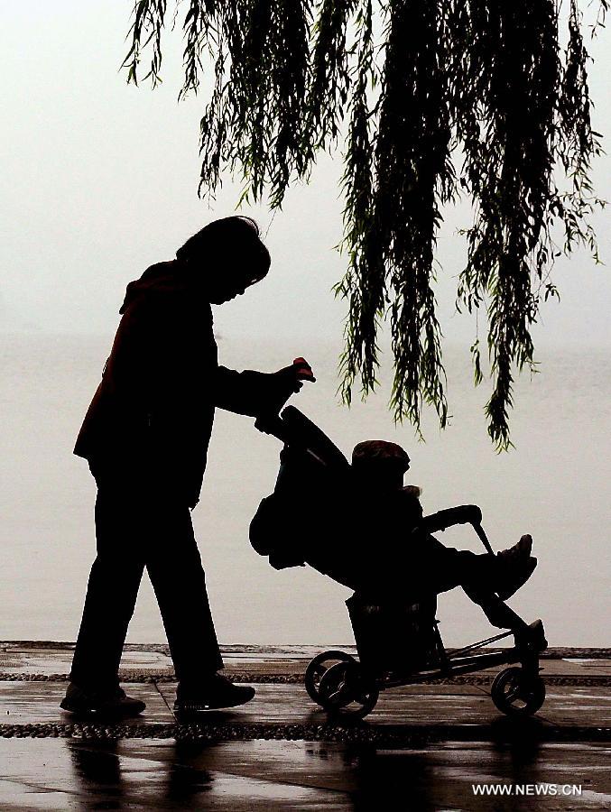 A woman pushes a pram by the West Lake in Hangzhou, capital of east China's Zhejiang Province, Nov. 4, 2013