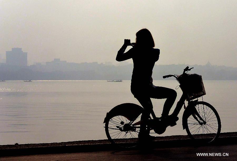 Tourists take photos by the West Lake in Hangzhou, capital of east China's Zhejiang Province, Nov. 4, 2013. 