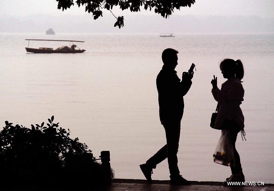 Tourists take photos by the West Lake in Hangzhou, capital of east China's Zhejiang Province, Nov. 4, 2013. 