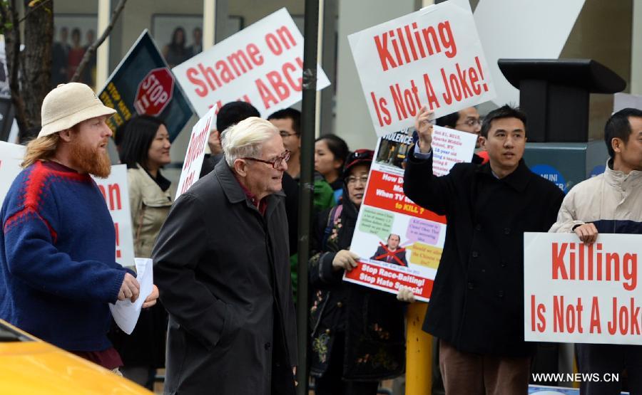 Two local persons pass by as protestors rally in front of the headquarters of the American Broadcasting Company (ABC) to protest against its rhetoric of racial discrimination in New York, the United States, Nov. 8, 2013. [Xinhua]