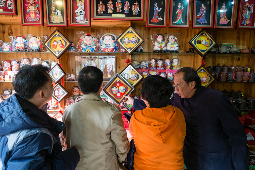 Tourists visit the Huishan Clay-figurine Workshop in Wuxi, Jiangsu Province, on Nov. 23, 2013. Clay figurines in this area have a long history. The region is famous for its fine craftsmanship. In 2006 it was included in the national intangible cultural heritage list, although it has been difficult to find talent in recent years. [Translated by Li Jingrong. Photo/Xinhua]