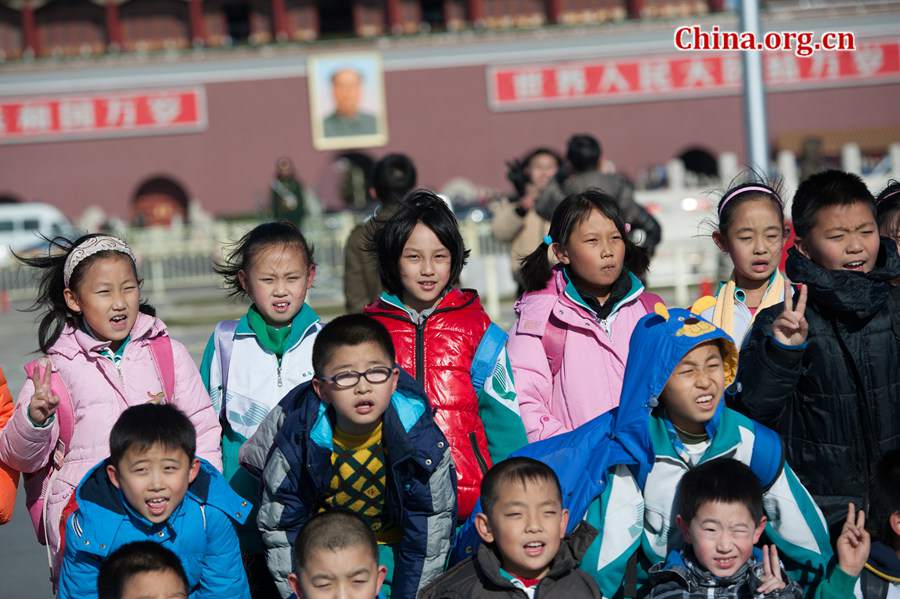 Tourists in Tian'anmen Square defy coldness in Beijing and pose for photos before the national flag stand on Wednesday. A strong cold snap that swept north China on Wednesday has brought down Beijing's temperature to below freezing point, sending the city into the depth of winter. The strong wind has completely dispersed the smog that used to hover above the Chinese capital. [Photo by Chen Boyuan / China.org.cn]