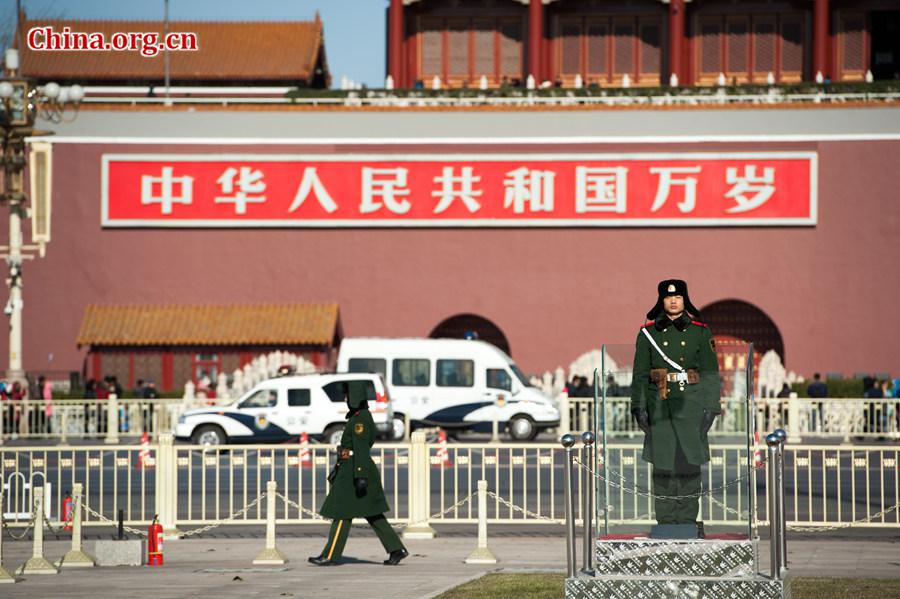 Tourists in Tian'anmen Square defy coldness in Beijing and pose for photos before the national flag stand on Wednesday. A strong cold snap that swept north China on Wednesday has brought down Beijing's temperature to below freezing point, sending the city into the depth of winter. The strong wind has completely dispersed the smog that used to hover above the Chinese capital. [Photo by Chen Boyuan / China.org.cn]