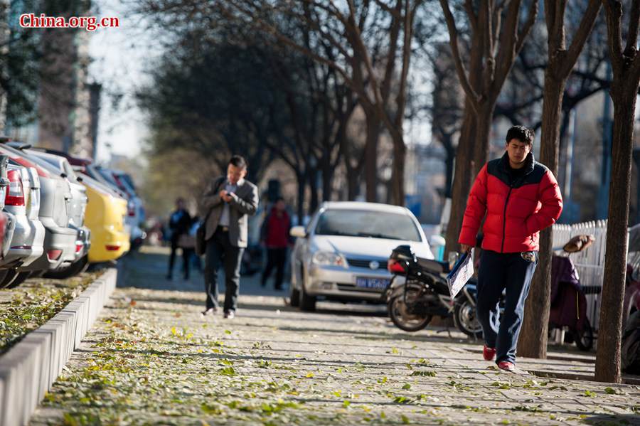 Tourists in Tian'anmen Square defy coldness in Beijing and pose for photos before the national flag stand on Wednesday. A strong cold snap that swept north China on Wednesday has brought down Beijing's temperature to below freezing point, sending the city into the depth of winter. The strong wind has completely dispersed the smog that used to hover above the Chinese capital. [Photo by Chen Boyuan / China.org.cn]