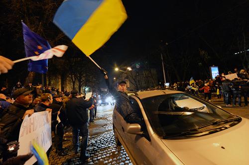 A protester waves a flag of Ukraine as he greets protesters from a car during a rally on Mykhayllivska Square in Kiev on November 30, 2013.[Xinhua photo]