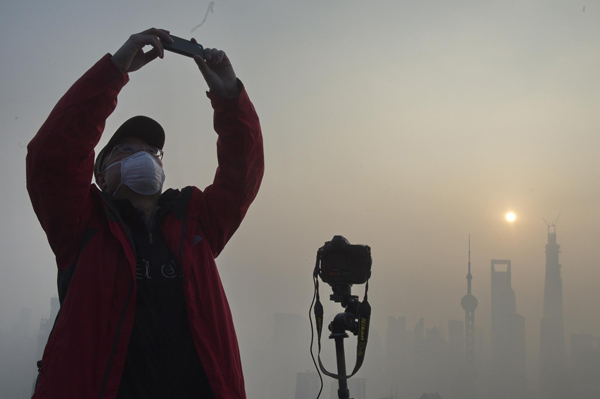 A resident in Shanghai takes a photo of the city's scenery amid heavy smog on Dec 7. 