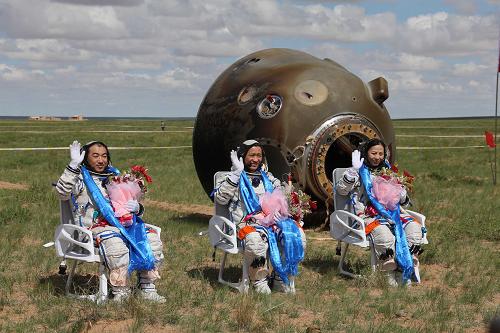 From left to right: astronauts Zhang Xiaoguang, Nie Haisheng and Wang Yaping are seen outside the return capsule of Shenzhou 10 spacecraft after it landed successfully on June 26, 2013. [Photo: Xinhua] 