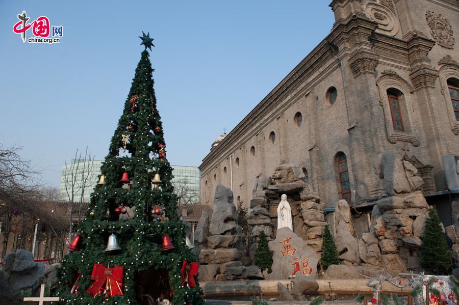 The Cathedral of the Immaculate Conception (colloquially known as the Xuanwumen Church, the South Church, or Nantang) in Beijing sets up a huge Christmas tree with a miniature of nativity that overlooks a smaller statue of Virgin Mary in its yard on Christmas Day, Dec. 25. [Photo by Chen Boyuan / China.org.cn]