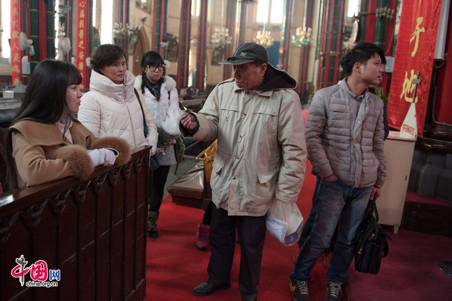 A Christian volunteer (R2) recounts the story of nativity to new comers in the Church of the Saviour (colloquially referred to as Xishiku Church, or Beitang -- the North Cathedral) in Beijing on the afternoon of Dec. 25, 2013, the Christmas Day. [Photo by Chen Boyuan / China.org.cn]