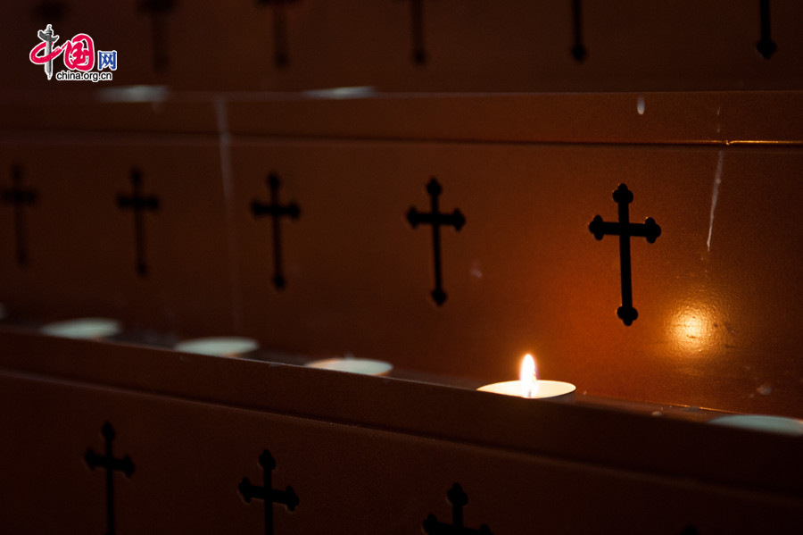 The Church of the Saviour (colloquially referred to as Xishiku Church, or Beitang -- the North Cathedral) in Beijing lights a candle on the stand on the afternoon of Dec. 25, 2013, the Christmas Day. [Photo by Chen Boyuan / China.org.cn]