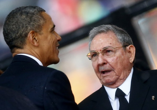 U.S. President Barack Obama (L) greets Cuban President Raul Castro before giving his speech at the memorial service for late South African President Nelson Mandela at the First National Bank soccer stadium, also known as Soccer City, in Johannesburg December 10, 2013. [Photo/China Daily]