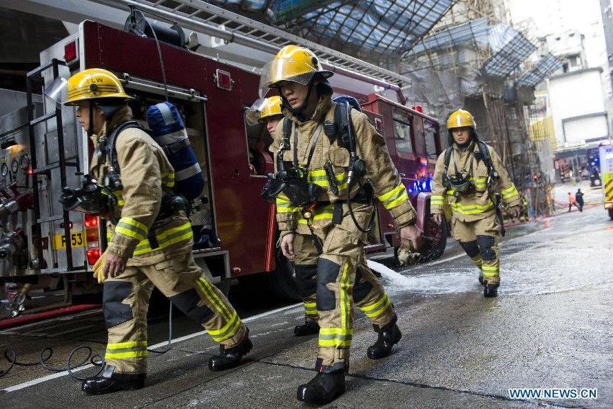 Firefighters work at the accident site after a fire erupted at a scaffolding outside Fung Wah Mansion on Cheung Hong street in North Point of Hong Kong, south China, Dec. 29, 2013. More than 20 people were injured in the fire on Sunday morning. (Xinhua/Lui Siu Wai) 