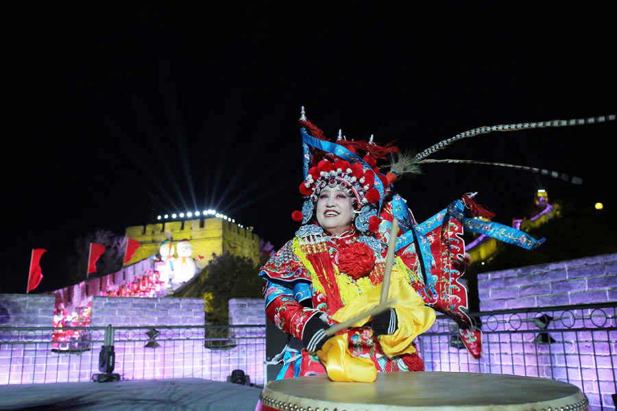 A woman dressed in an opera outfit plays drums at Badaling section of the Great Wall to celebrate the upcoming New Year of 2014 during a countdown ceremony in Beijing on Dec 31, 2013. [Photo by Wang Jing / China Daily]