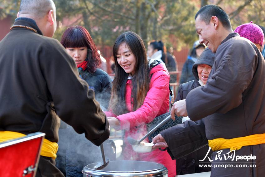 Visitors to the Yonghe Lama Temple in Beijing get their free bowl of Laba porridge offered by the temple on January 8, 2014, which is the Laba Festival according to the Chinese lunar calendar. Eating Laba porridge is a tradition for those who wish to enjoy a good year via this special food made of eight ingredients, also known as the &apos;eight treasures.&apos; 