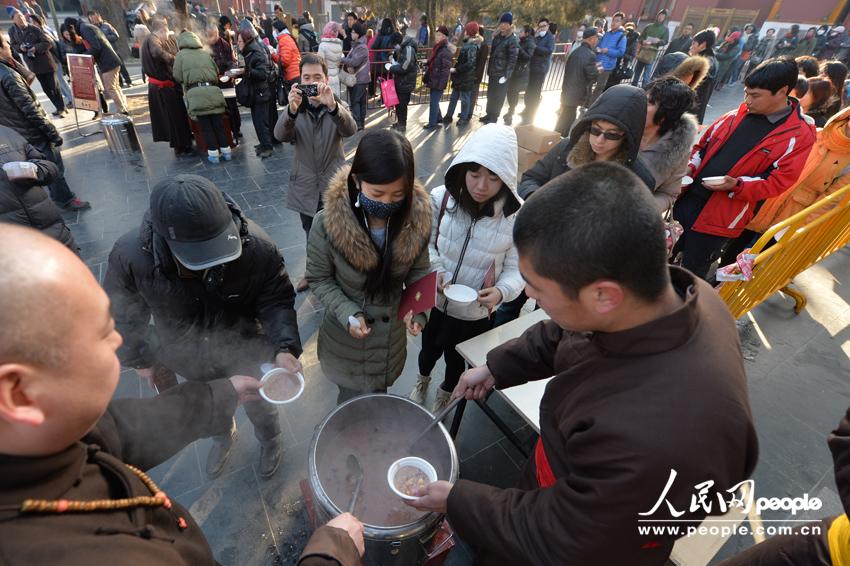 Visitors to the Yonghe Lama Temple in Beijing get their free bowl of Laba porridge offered by the temple on January 8, 2014, which is the Laba Festival according to the Chinese lunar calendar. Eating Laba porridge is a tradition for those who wish to enjoy a good year via this special food made of eight ingredients, also known as the &apos;eight treasures.&apos; 