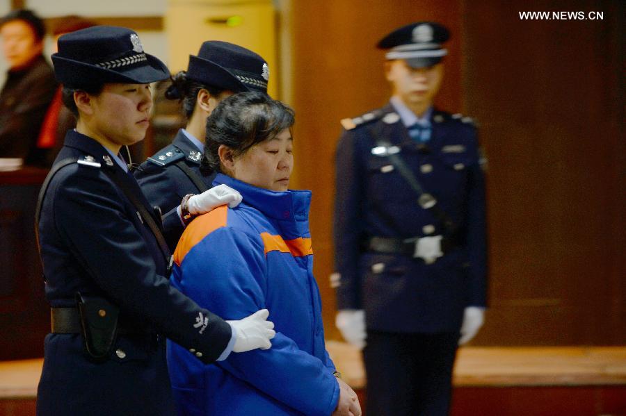 Zhang Shuxia (2nd R), an obstetrician in northwest China's Shaanxi Province, who is involved in a baby trafficking scandal, is escorted off the Weinan Intermediate People's Court in Weinan, Shaanxi Province, Jan. 14, 2014. Zhang was sentenced to death with a two years' reprieve on Tuesday for trafficking seven babies, a local court said. [photo / Xinhua]