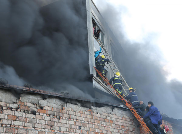 Firefighters work with local residents to rescue the workers trapped in a factory fire in Wenling city, East China's Zhejiang province, on Jan 14, 2014. [Photo/Xinhua]