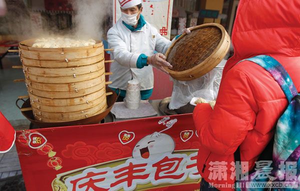 2月11日，长沙世界之窗，游客在“庆丰包子”摊位前买包子。[潇湘晨报 华剑 摄]