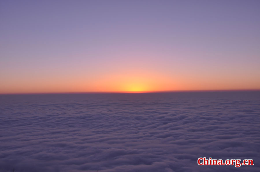 日出是峨眉山顶的又一自然殊景，奇妙壮观。在海拔3000多米的峨眉山金顶，远望东方，地平线在水平视线以下，橙红的太阳冒出水平线，伴有云层作陪，尽显浩瀚壮阔。[中国网 陈祥昭 摄]